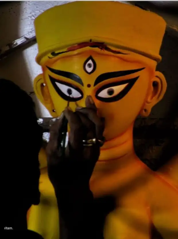 An artisan painting the eyes onto the idol before the Puja